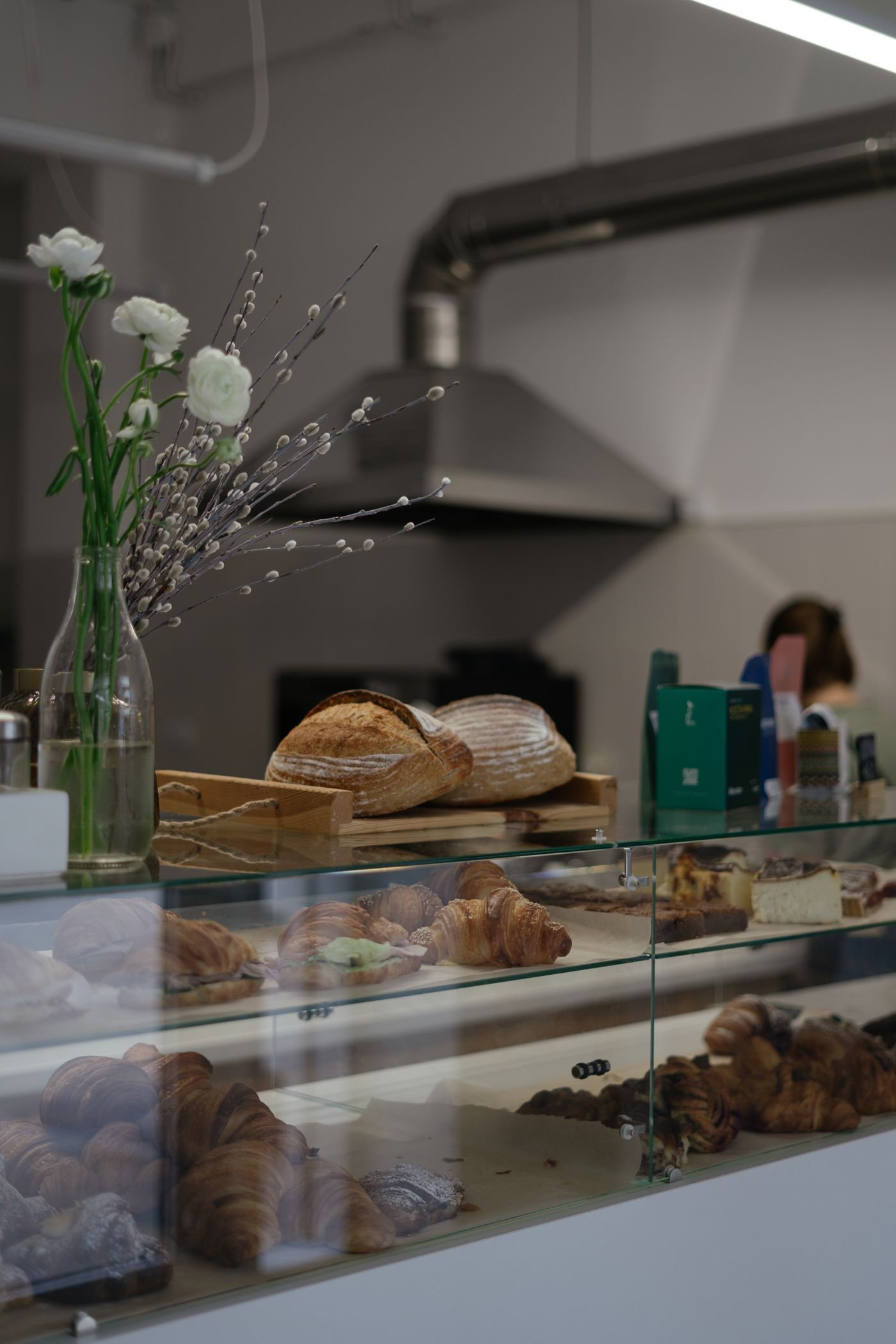 A bakery counter with croissants, loaves and flowers
