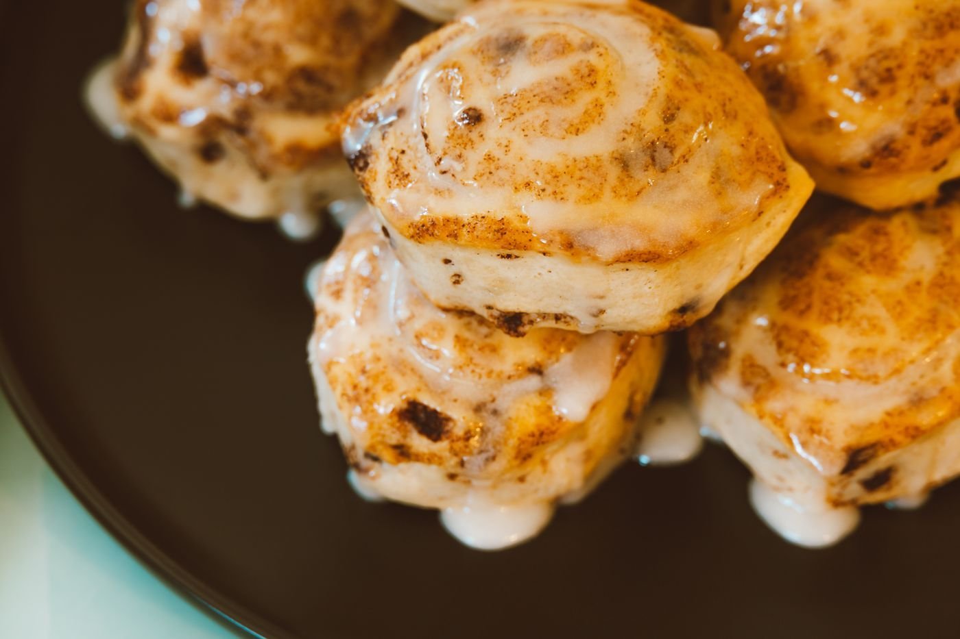 Glazed cinnamon buns stacked on a plate